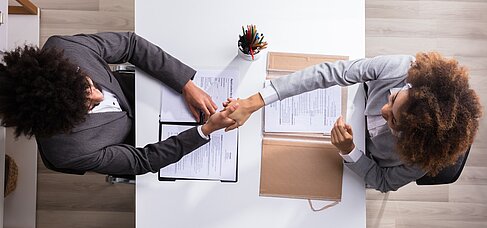 Zwei Menschen geben sich zum Vertragsschluss die Hand